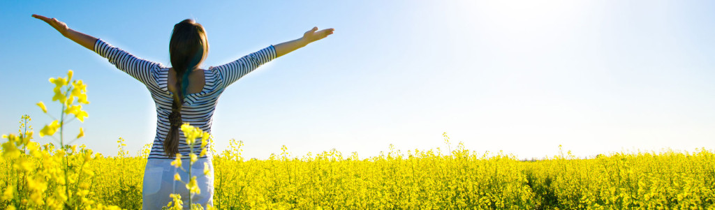 lady in a field of flowers with arms up signifying freedom